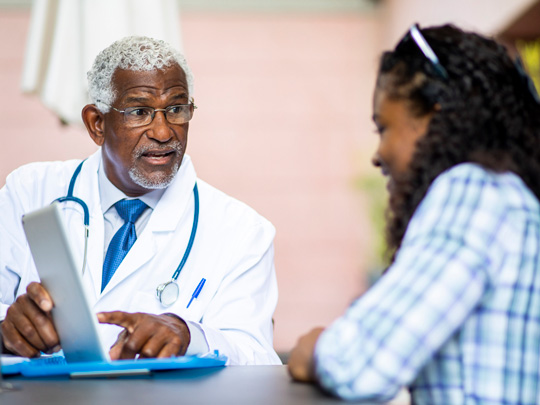 A doctor discusses results on a computer with a patient.