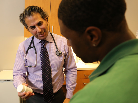 provider holding medicine bottle talking with male patient
