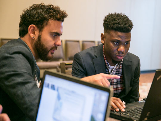 Two men look at computers at a virtual office hours session.