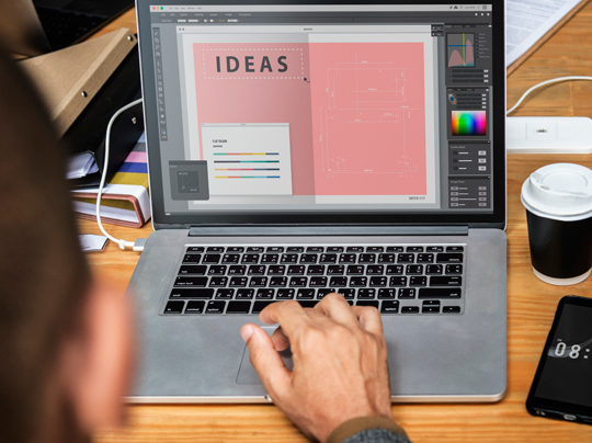 A man types on his laptop with the words Ideas written across the monitor.